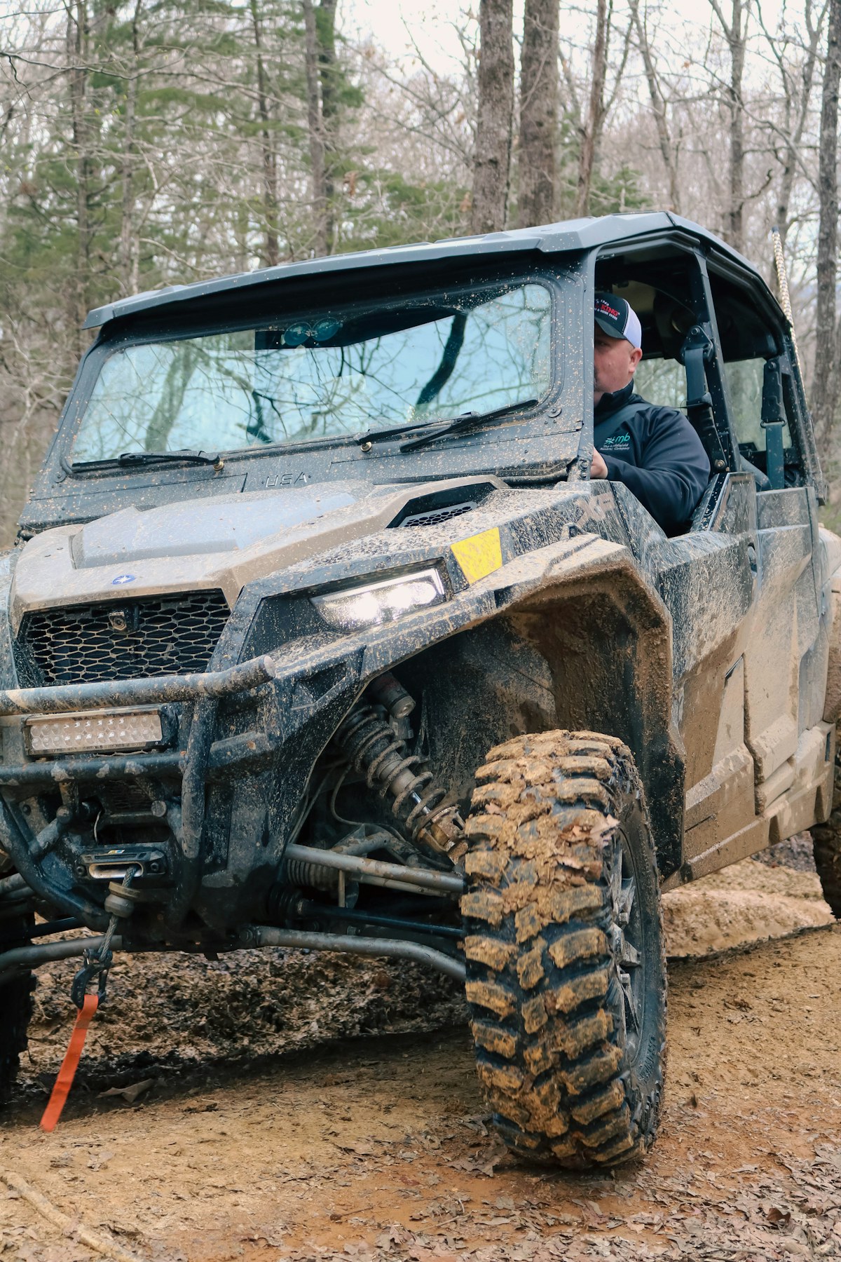 Rider on an ATV splashing through a muddy forest trail.
